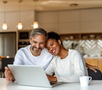 Couple smiling at laptop in kitchen